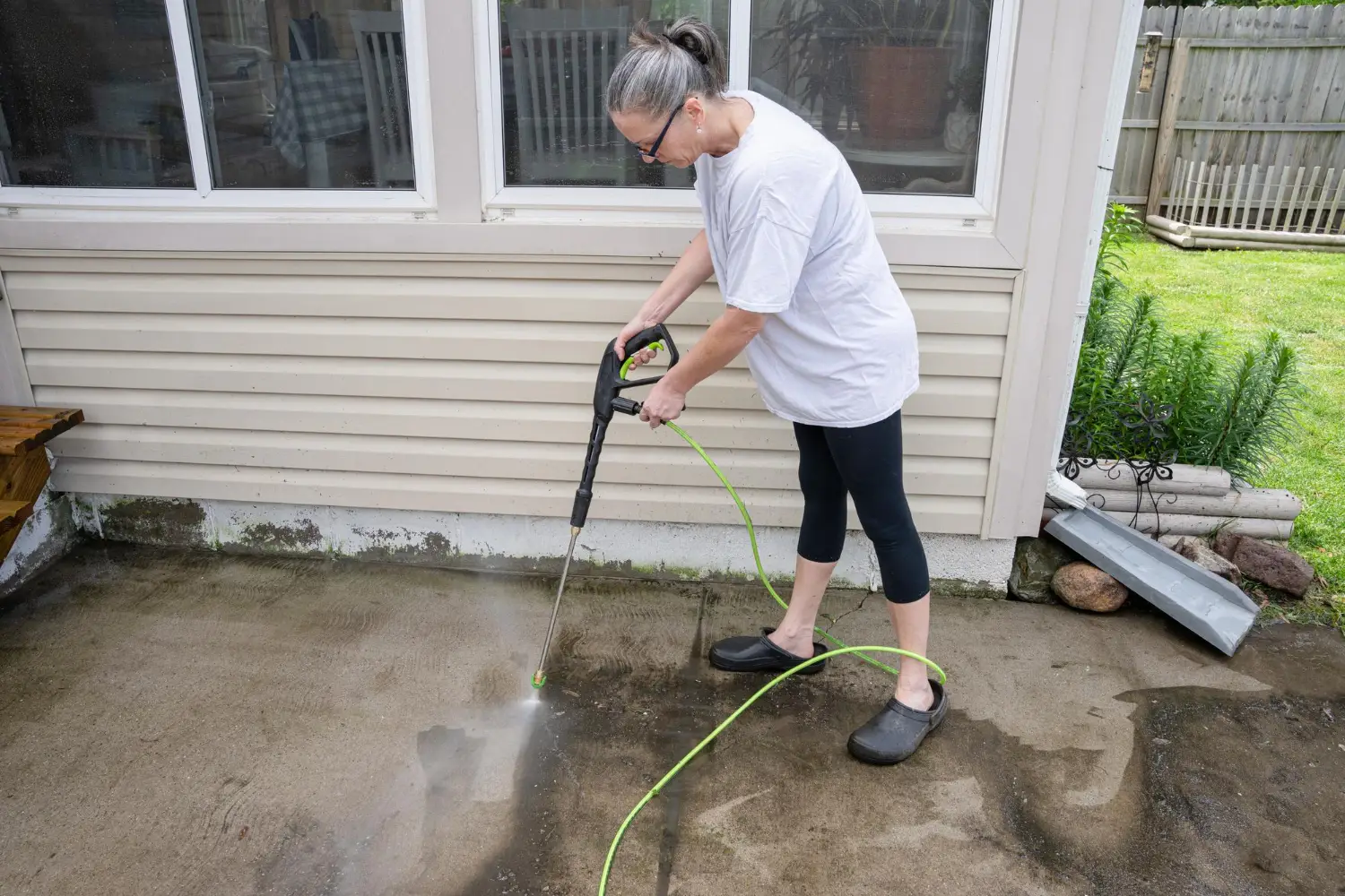 Pressure washing dirt off a patio.